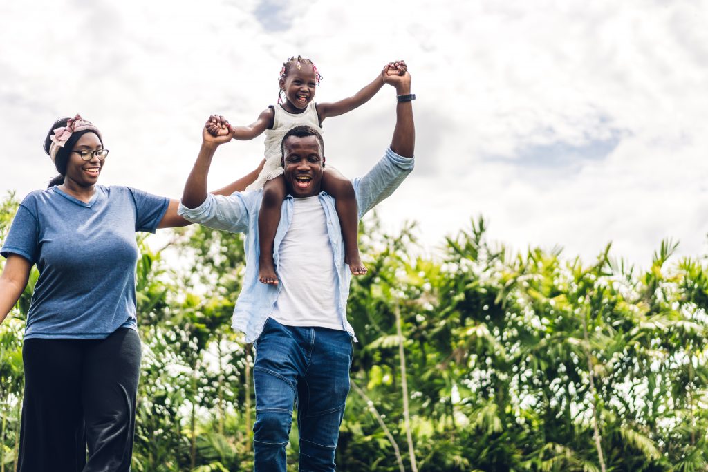 famille noire enfant sur épaules parents joie lien familial