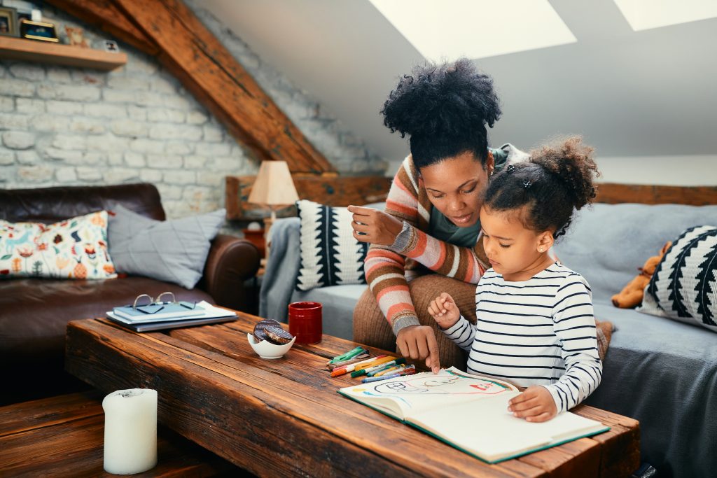Maman et sa fille échangeant autour d’un cahier, dans un moment de communication favorisant le développement du langage chez l’enfant