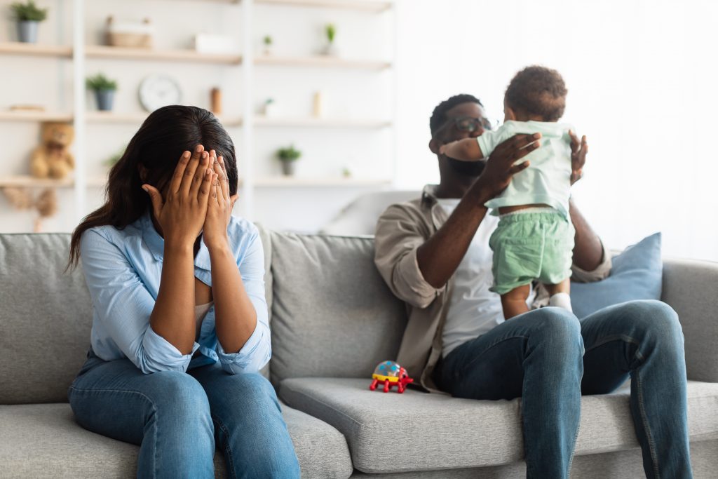 maman réfléchit sur canapé père joue enfant famille noire