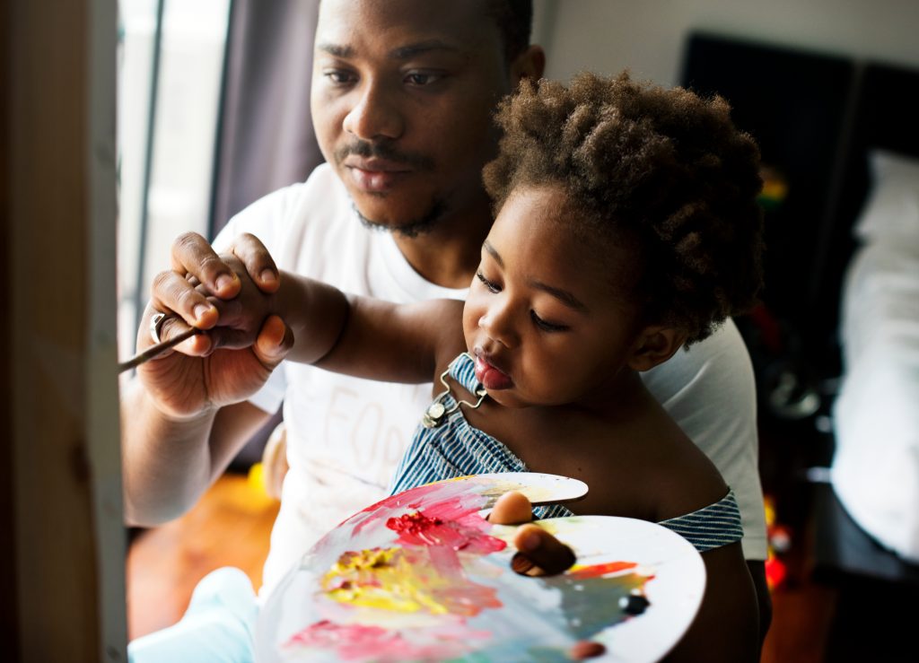 Père et sa fille en train de peindre ensemble, dans un moment d’expression créative participant au développement du langage et de la communication